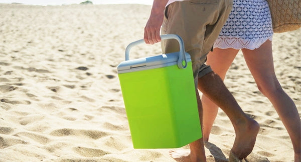 cropped photo of couple walking on the beach with a cooler
