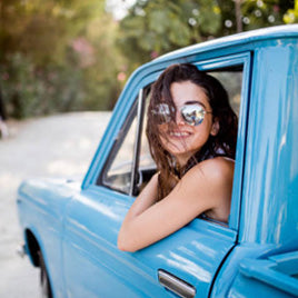 Woman in sunglasses looking out from the window of a blue truck